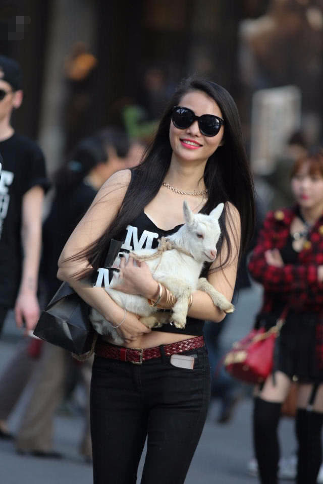 怀抱小羊的小姐姐牛仔裤搭配黑色小背心，有爱心的女人很美