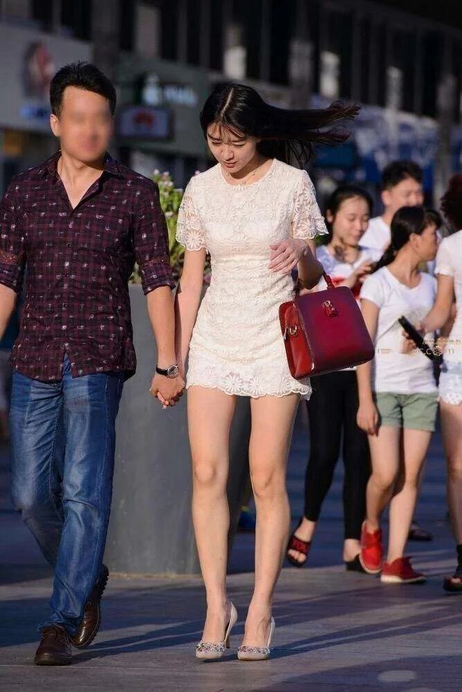 走在街上的小姐姐身穿白色连衣裙，展示出别致的美感