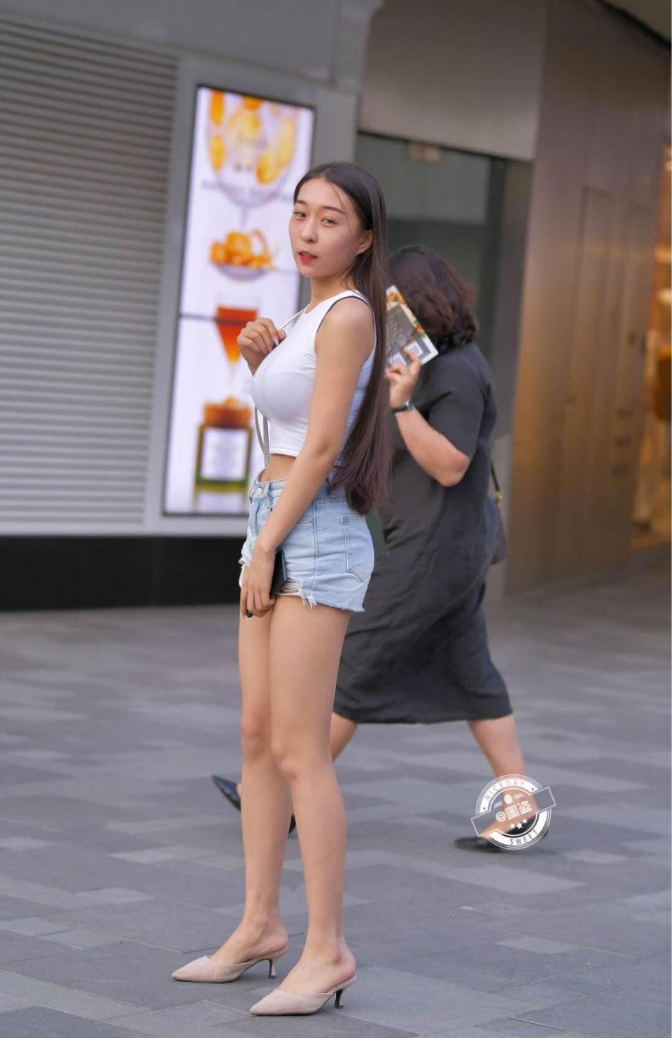路人街拍，小姐姐上身穿的是一件无袖的露脐紧身上衣，身材真好看