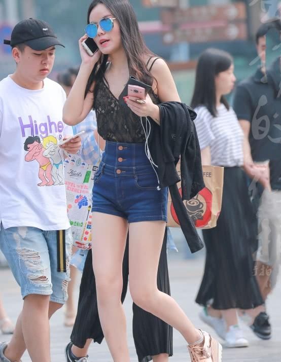 墨镜姐姐紧身牛仔短裤穿出修长大美腿，打电话的表情有些羞涩