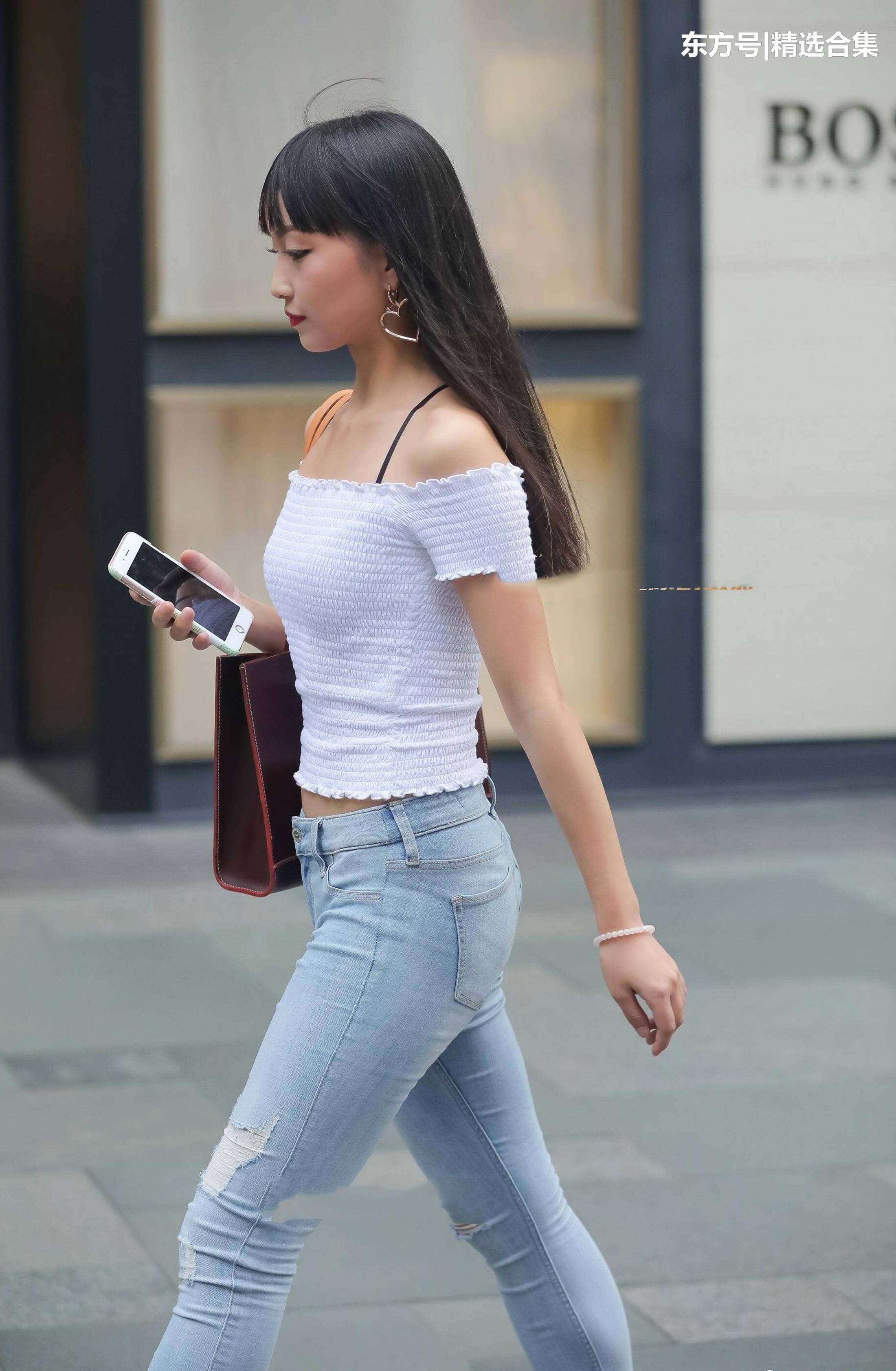 街拍美女:破洞紧身牛仔裤搭配白色漏肩针织衫，很素雅的小姐姐