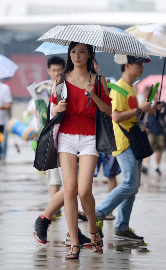 时尚小姐姐雨天上街，小热裤勾勒出修长美腿，伞下的她显得更加诱