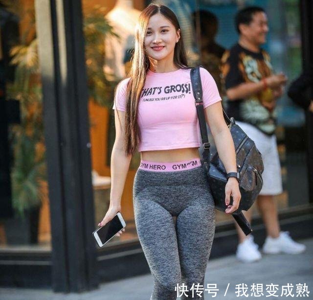 路人街拍，皮肤白皙的美女穿露脐装配紧身牛仔裤，身材妩媚而性感