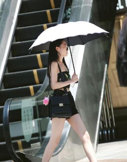 小美女:街拍:小美女身穿黑色套装,手里拿着包包,笑容甜美