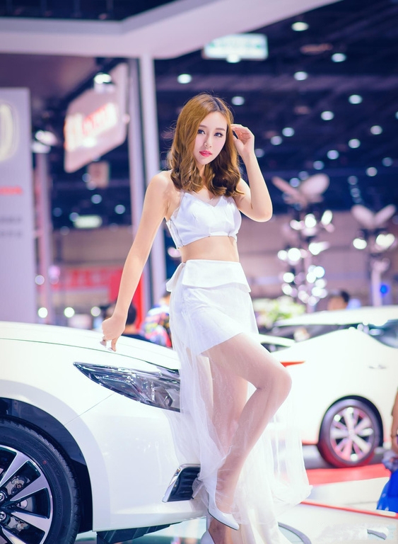 明艳娇俏的美女车模，白色纱裙自带满满仙气，笑容甜美引全场瞩目