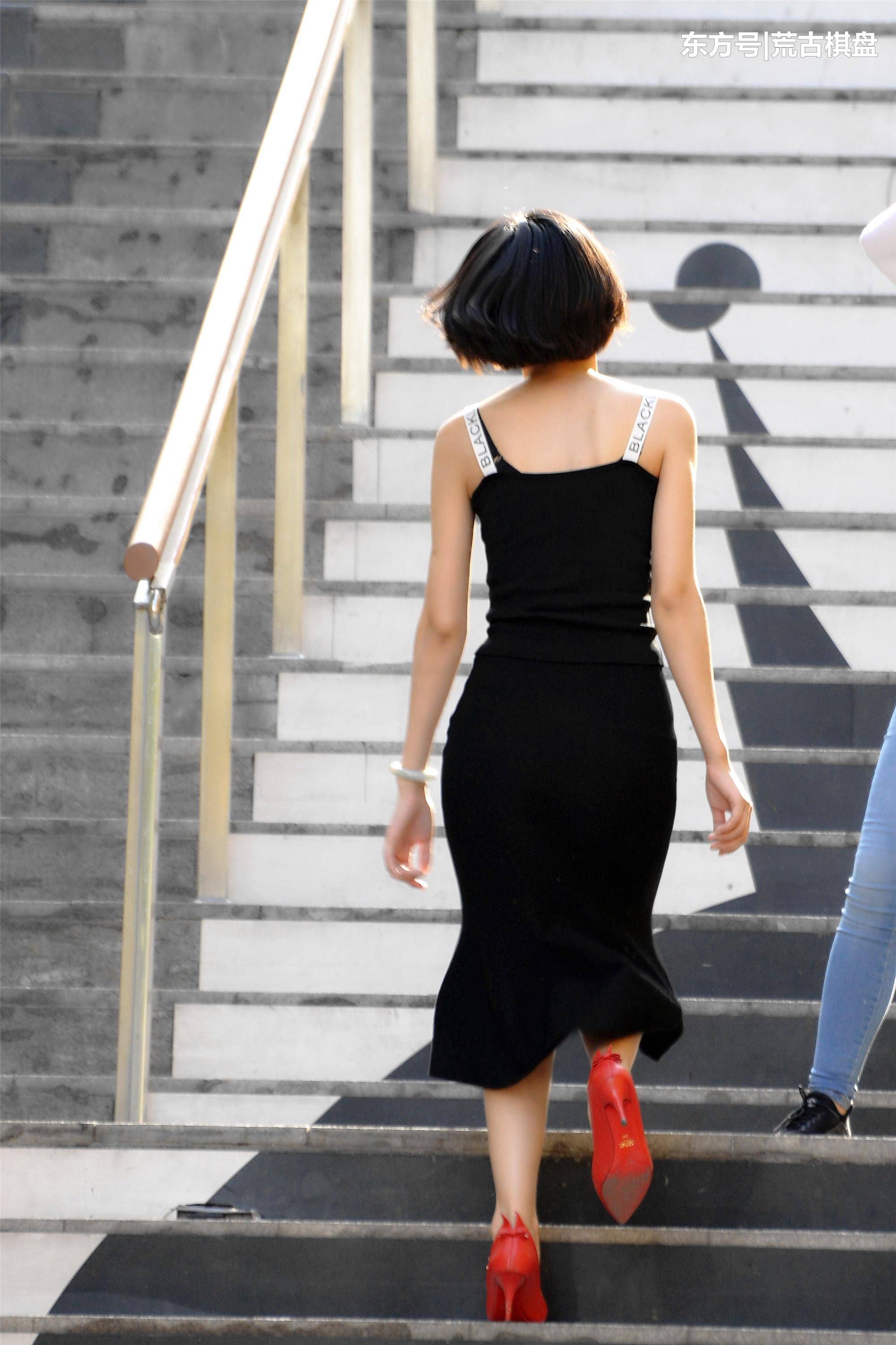 黑色吊带长裙姑娘穿着尖头细高跟在台阶上走上走下，忙碌着什么?