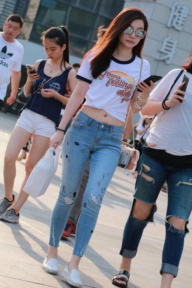 街拍，美丽小姐姐身穿露脐装配牛仔裤，时尚靓丽小蛮腰迷人