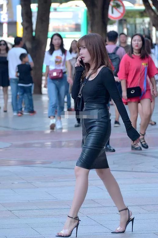 路人街拍，小姐姐穿着黑色紧身的小皮裙，露出白皙的小腿很迷人